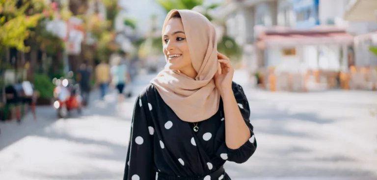Ung, smilende kvinne i hijab i en lys gate
