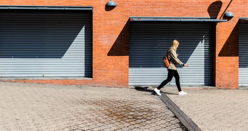 Ung kvinne går langs en vegg med garasjedører