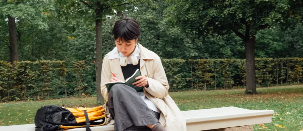 Ada Kristine Monstad skriver i en bok på en parkbenk