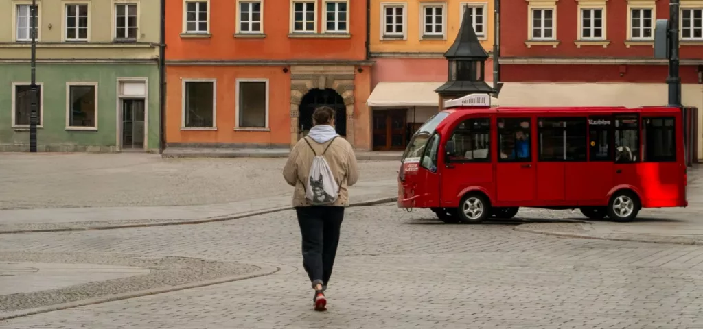 Kvinne går over et torg med en rød buss