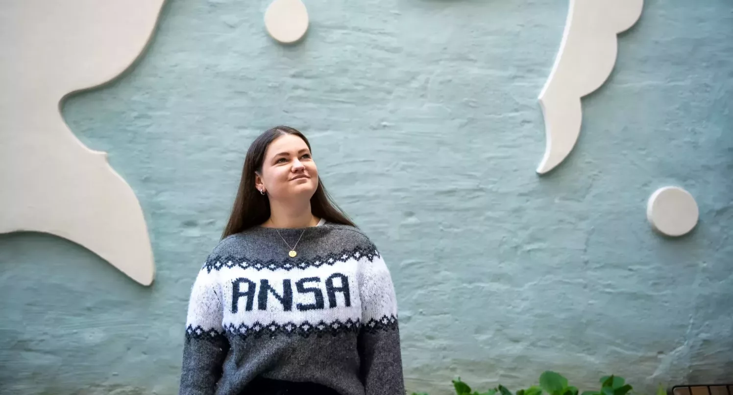Anna Handal Hellesnes med ANSA-genser foran blå vegg